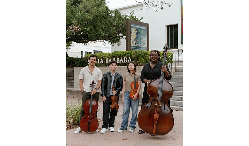 four young people with their string instruments standing near the front steps of the museum entrance